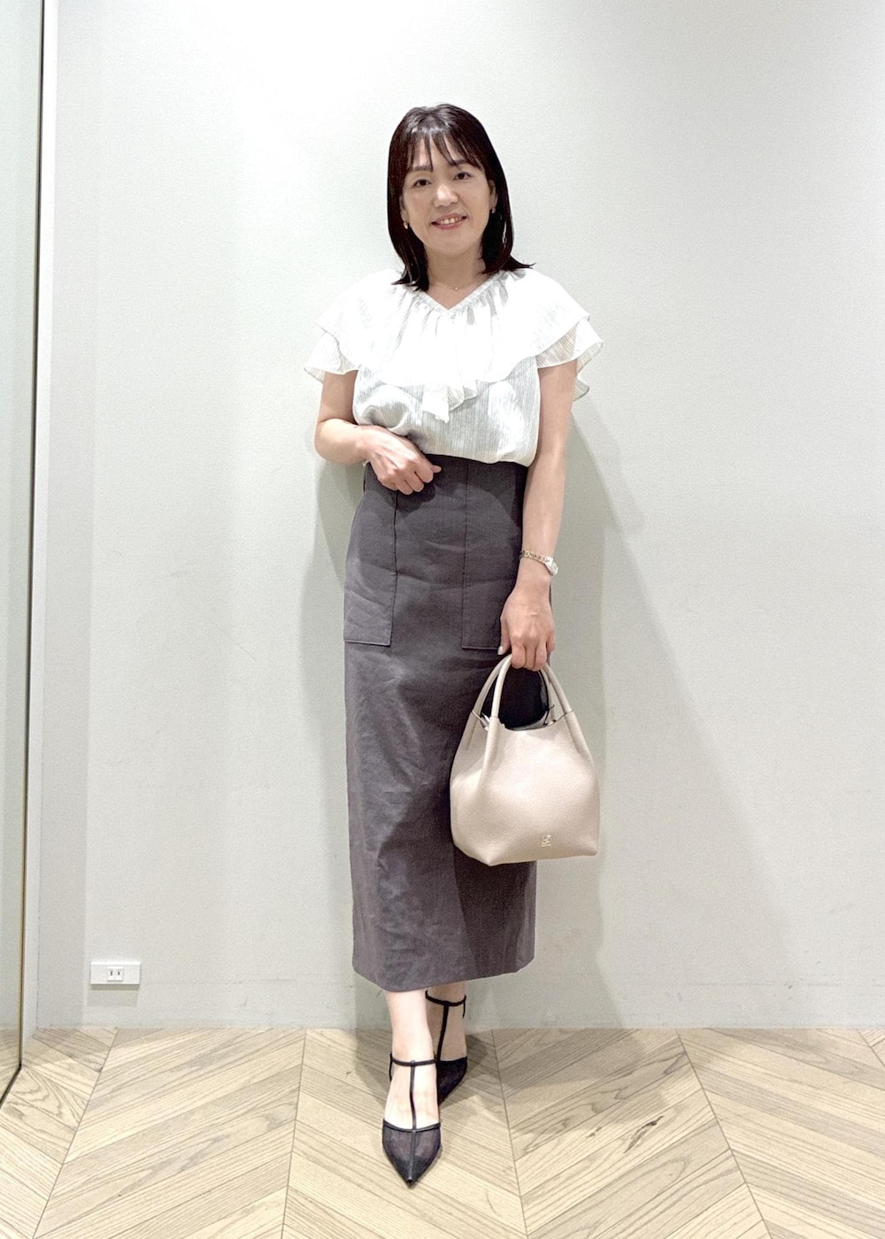 ブラック系のパンプス、グレー系のスカート、ホワイト系のシャツ/ブラウスを着用したレディースの夏コーディネートの10枚目の写真