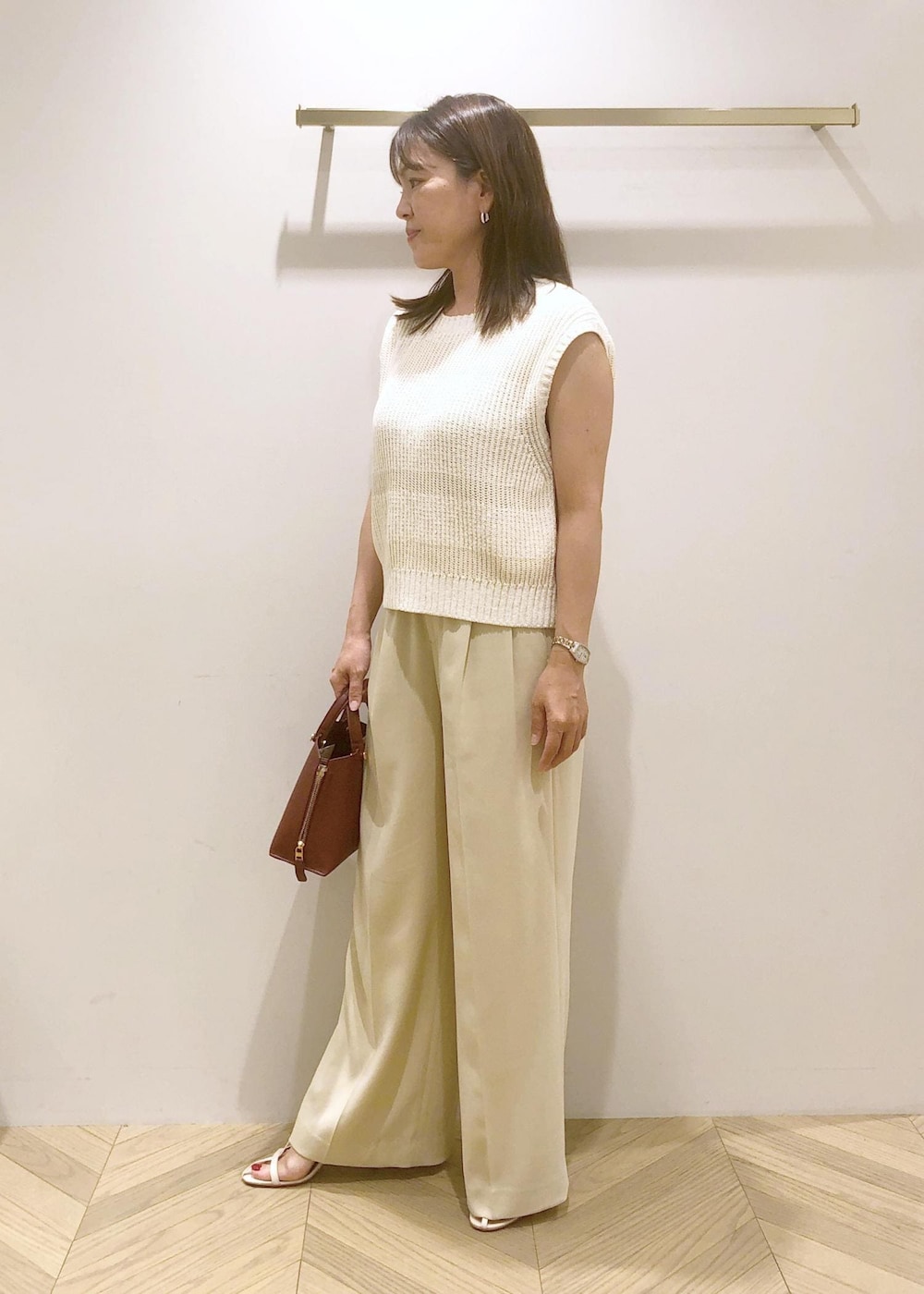 ホワイト系のサンダル、レッド系のハンドバッグ、ホワイト系のベストを着用したレディースの夏コーディネートの3枚目の写真