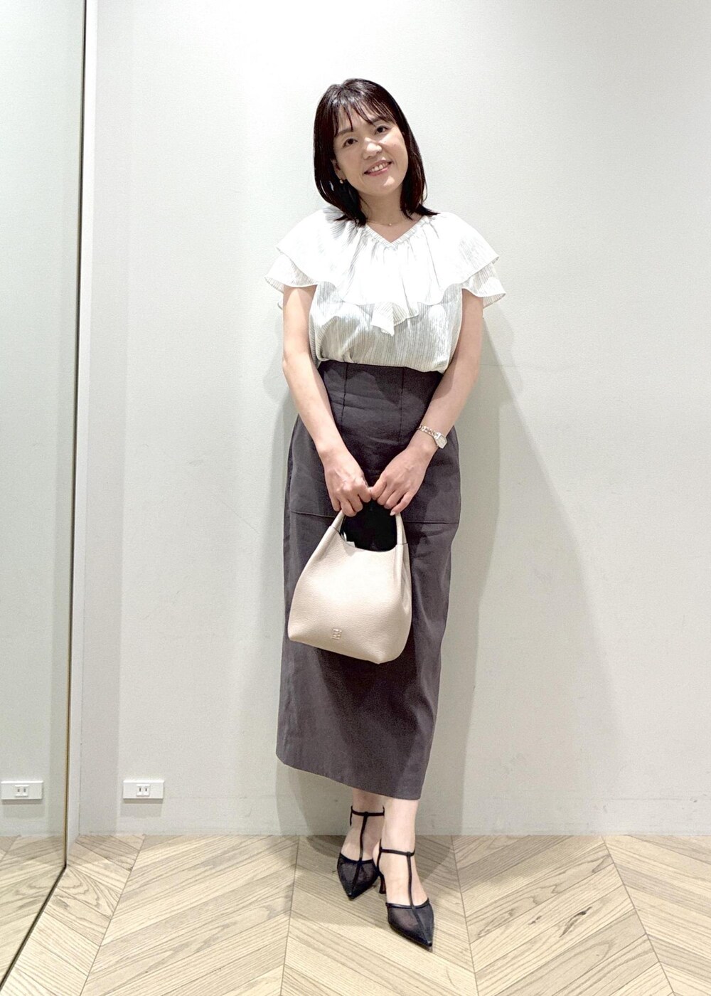 ブラック系のパンプス、グレー系のスカート、ホワイト系のシャツ/ブラウスを着用したレディースの夏コーディネートの4枚目の写真
