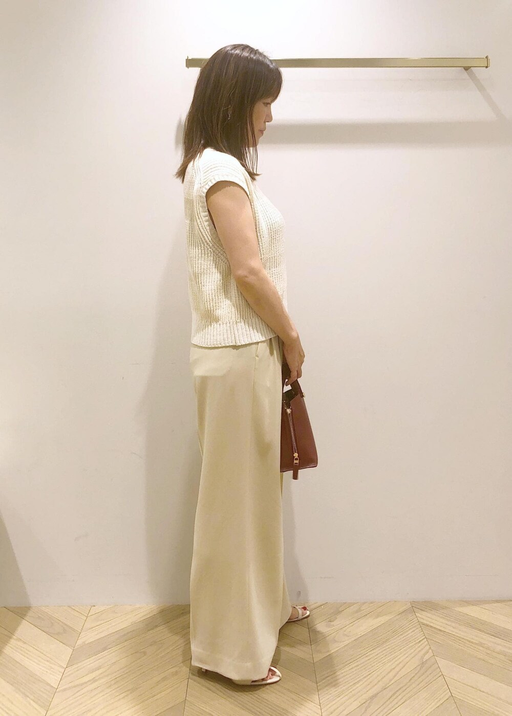 ホワイト系のサンダル、レッド系のハンドバッグ、ホワイト系のベストを着用したレディースの夏コーディネートの4枚目の写真