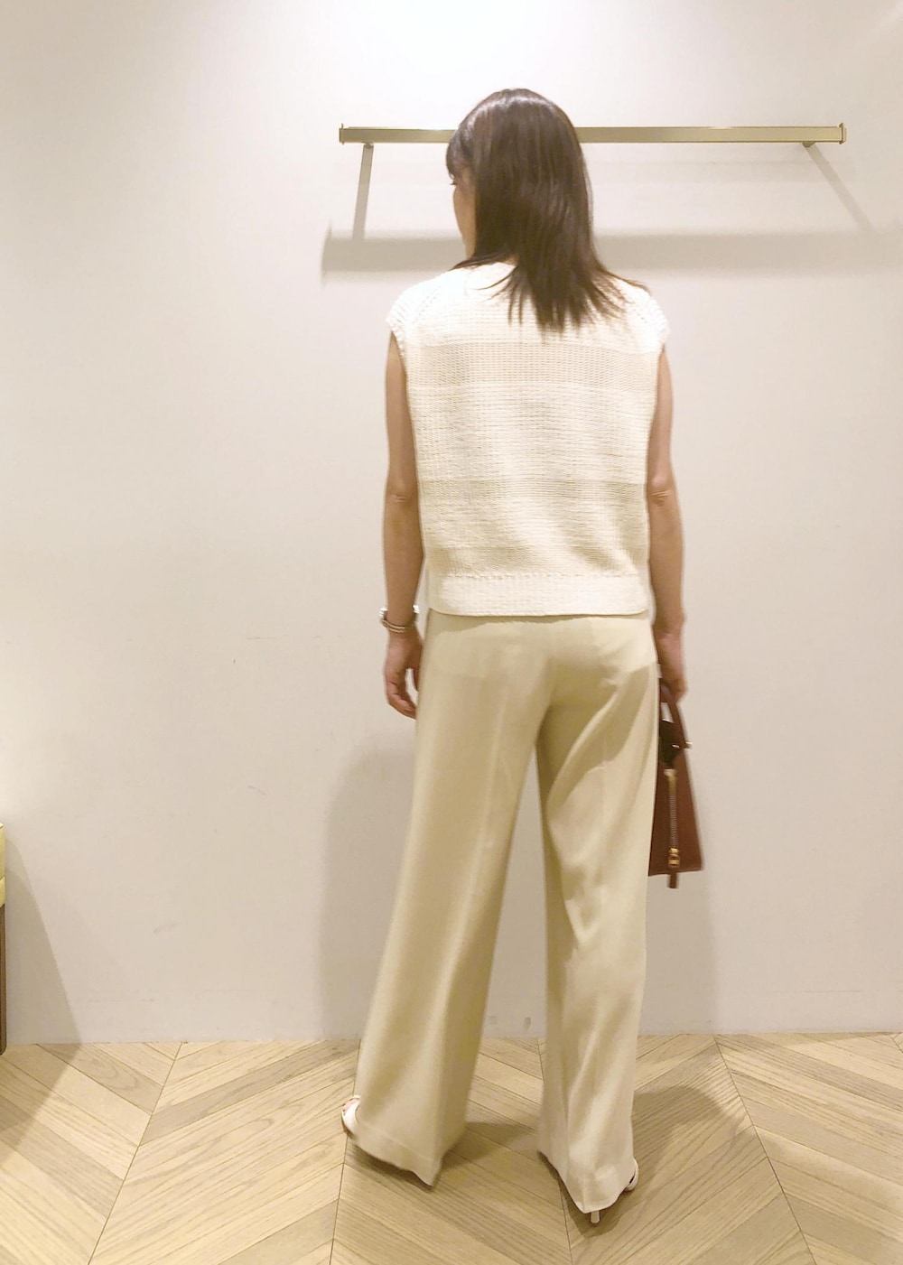 ホワイト系のサンダル、レッド系のハンドバッグ、ホワイト系のベストを着用したレディースの夏コーディネートの5枚目の写真