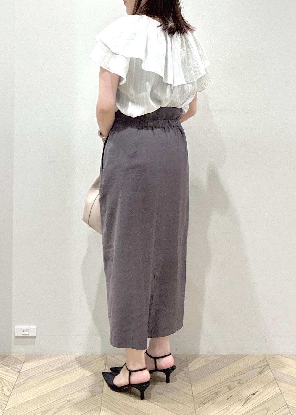 ブラック系のパンプス、グレー系のスカート、ホワイト系のシャツ/ブラウスを着用したレディースの夏コーディネートの6枚目の写真