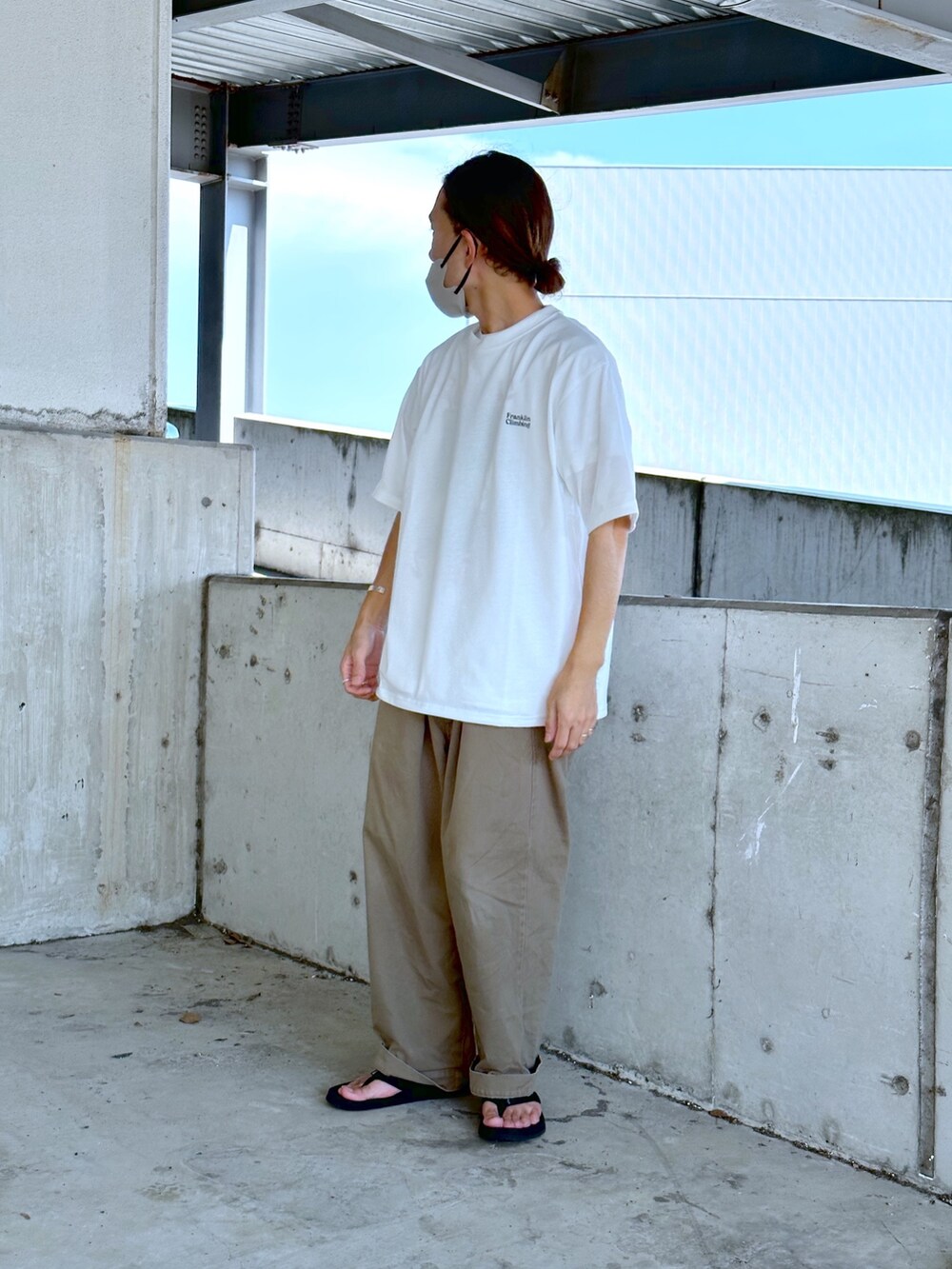 ホワイト系のTシャツ/カットソー、グリーン系のチノパンツ、ブラック系のサンダルを着用したメンズの夏コーディネートの2枚目の写真