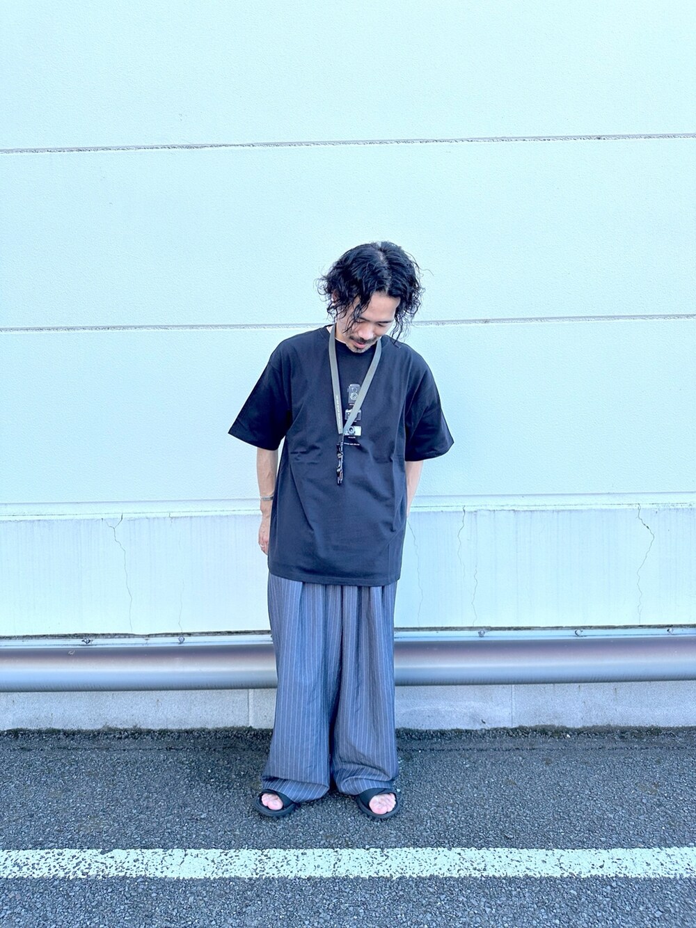 ブラック系のTシャツ/カットソー、グレー系のスラックスを着用したメンズの夏コーディネートの2枚目の写真