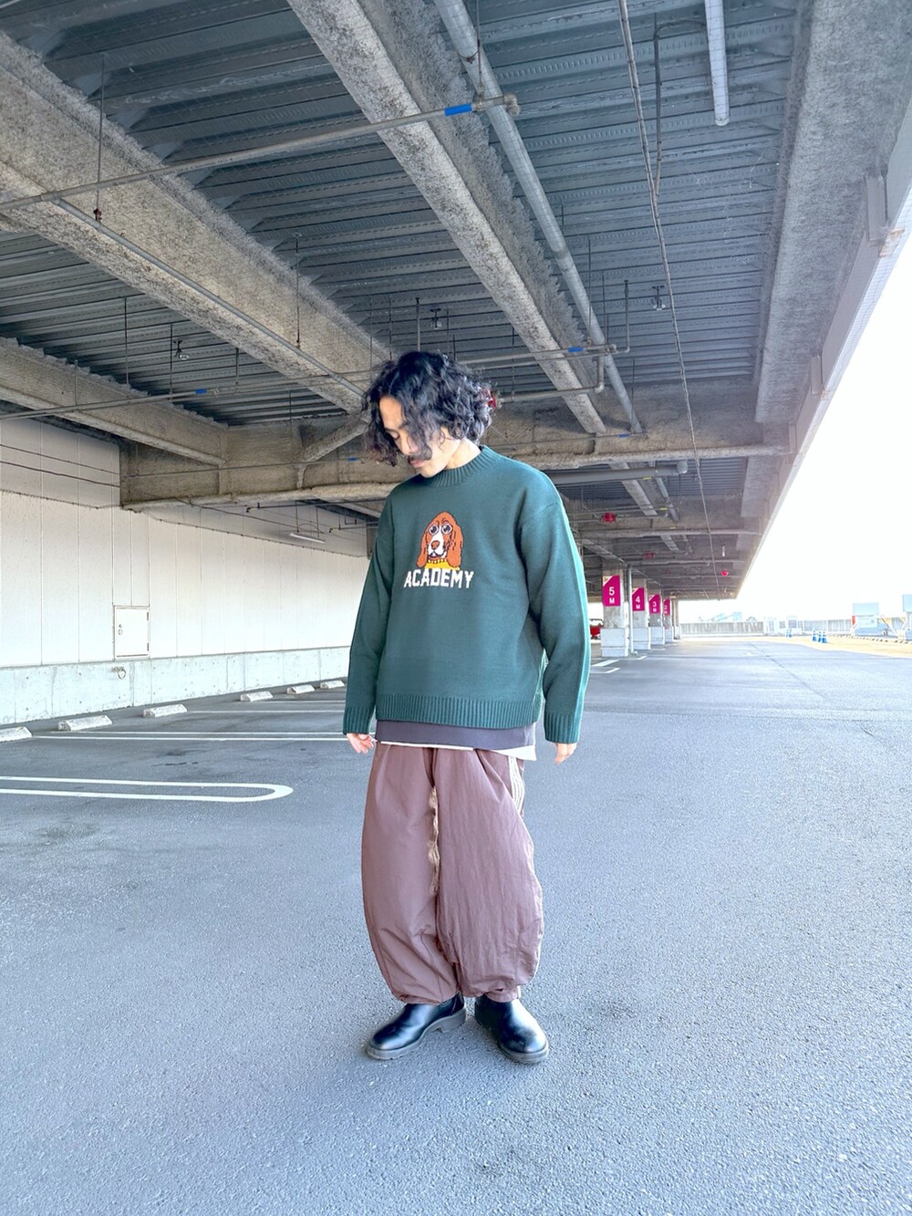 グリーン系のニット/セーター、ブラウン系のスウェットパンツを着用したメンズの秋コーディネートの2枚目の写真