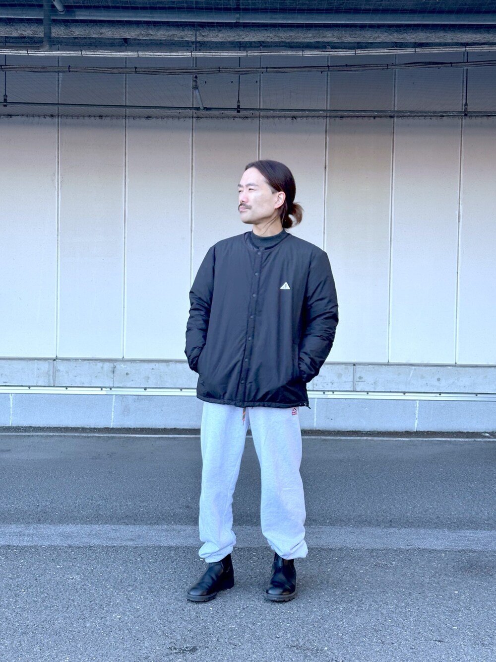 ブラック系のノーカラージャケット、グレー系のスウェットパンツ、ブラック系のブーツを着用したメンズの冬コーディネートの2枚目の写真