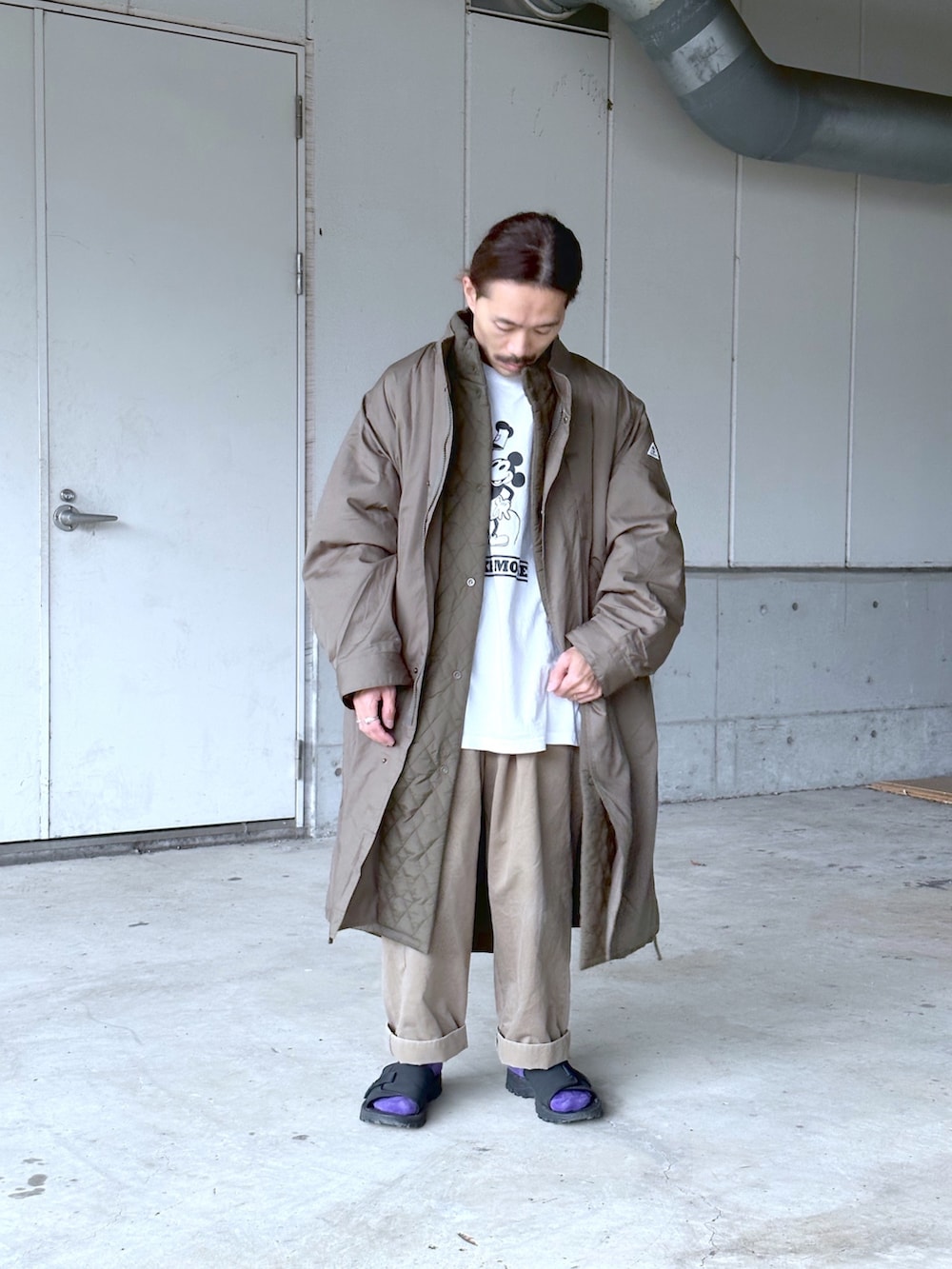 グリーン系のモッズコート、グリーン系のチノパンツ、ホワイト系のTシャツ/カットソーを着用したメンズの秋コーディネートの2枚目の写真