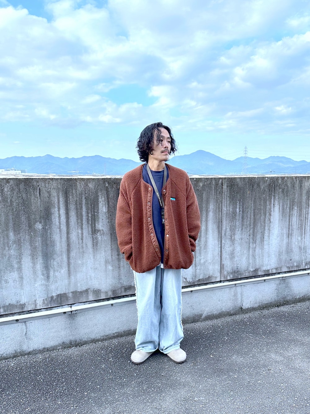 ブラウン系のブルゾン、ブルー系のデニムパンツを着用したメンズの秋コーディネートの2枚目の写真