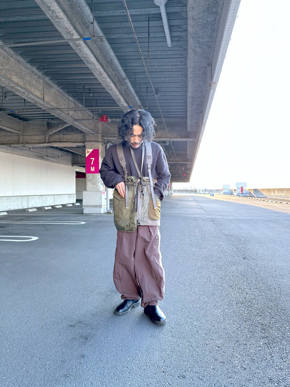 レッド系のスウェット、ブラウン系のスウェットパンツ、グリーン系のベストを着用したメンズの秋コーディネートの2枚目の写真