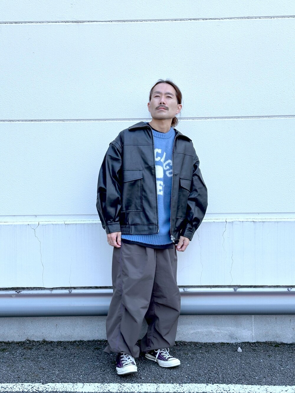 ブラック系のライダースジャケット、ブルー系のニット/セーター、ブラック系のカーゴパンツを着用したメンズの冬コーディネートの2枚目の写真
