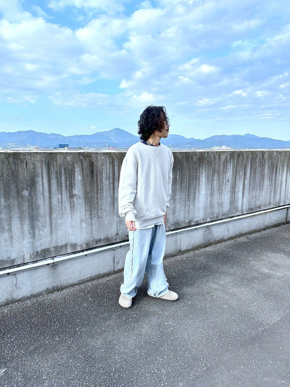 グレー系のスウェット、ブルー系のデニムパンツを着用したメンズの秋コーディネートの2枚目の写真