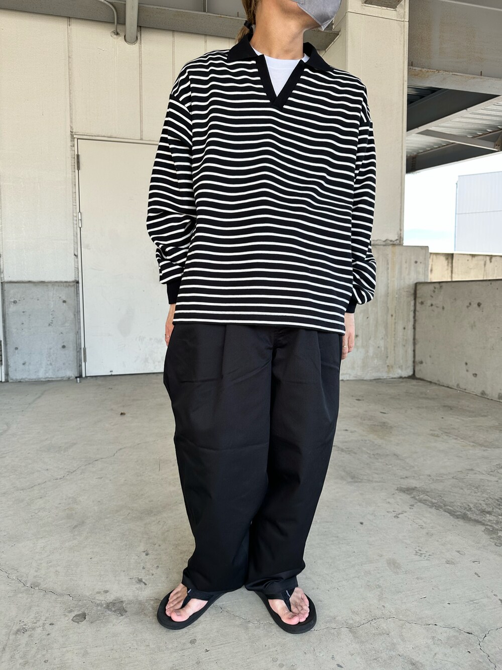 ブラック系のチノパンツ、ホワイト系のポロシャツ、ブラック系のサンダルを着用したメンズの夏コーディネートの2枚目の写真