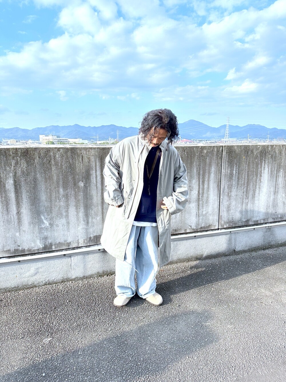 グレー系のミリタリージャケット、ブルー系のデニムパンツを着用したメンズの秋コーディネートの2枚目の写真