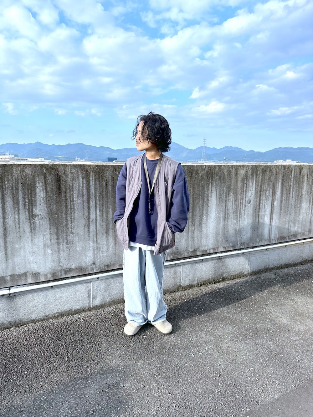 グレー系のベスト、ブルー系のデニムパンツを着用したメンズの秋コーディネートの2枚目の写真