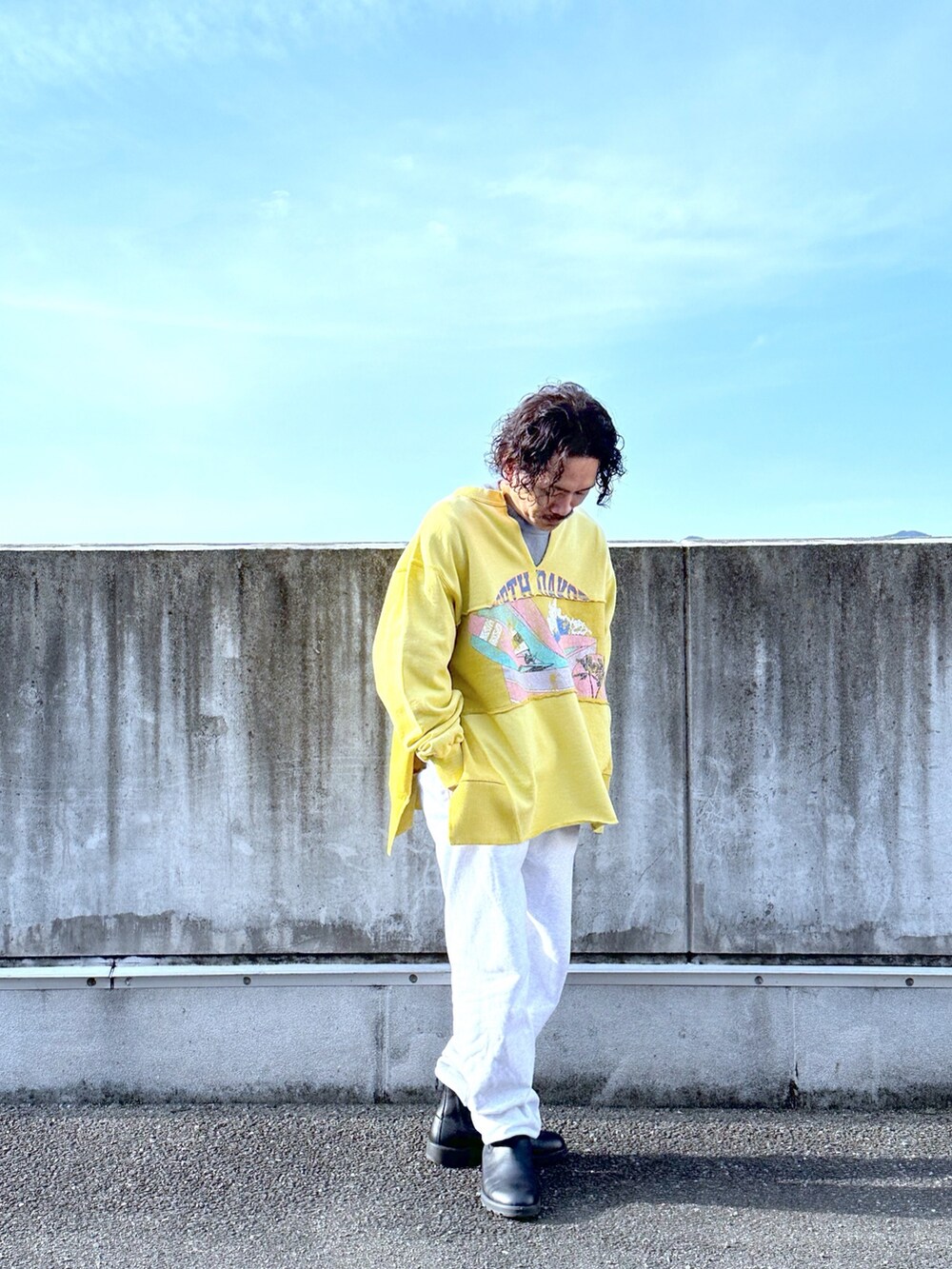 イエロー系のスウェット、グレー系のスウェットパンツ、ブラック系のブーツを着用したメンズの春コーディネートの2枚目の写真