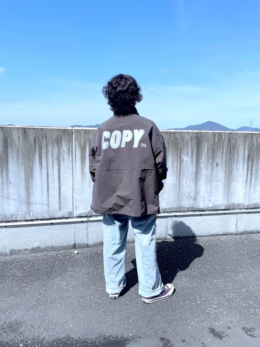 グレー系のナイロンジャケット、ブルー系のデニムパンツを着用したメンズの春コーディネートの2枚目の写真