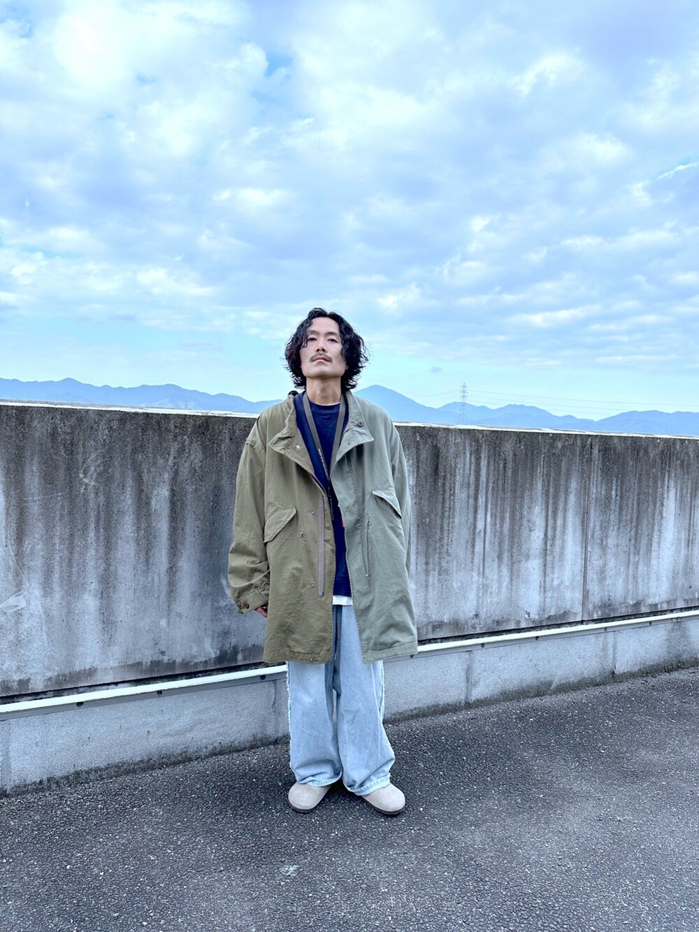 グリーン系のモッズコート、ブルー系のデニムパンツを着用したメンズの秋コーディネートの2枚目の写真