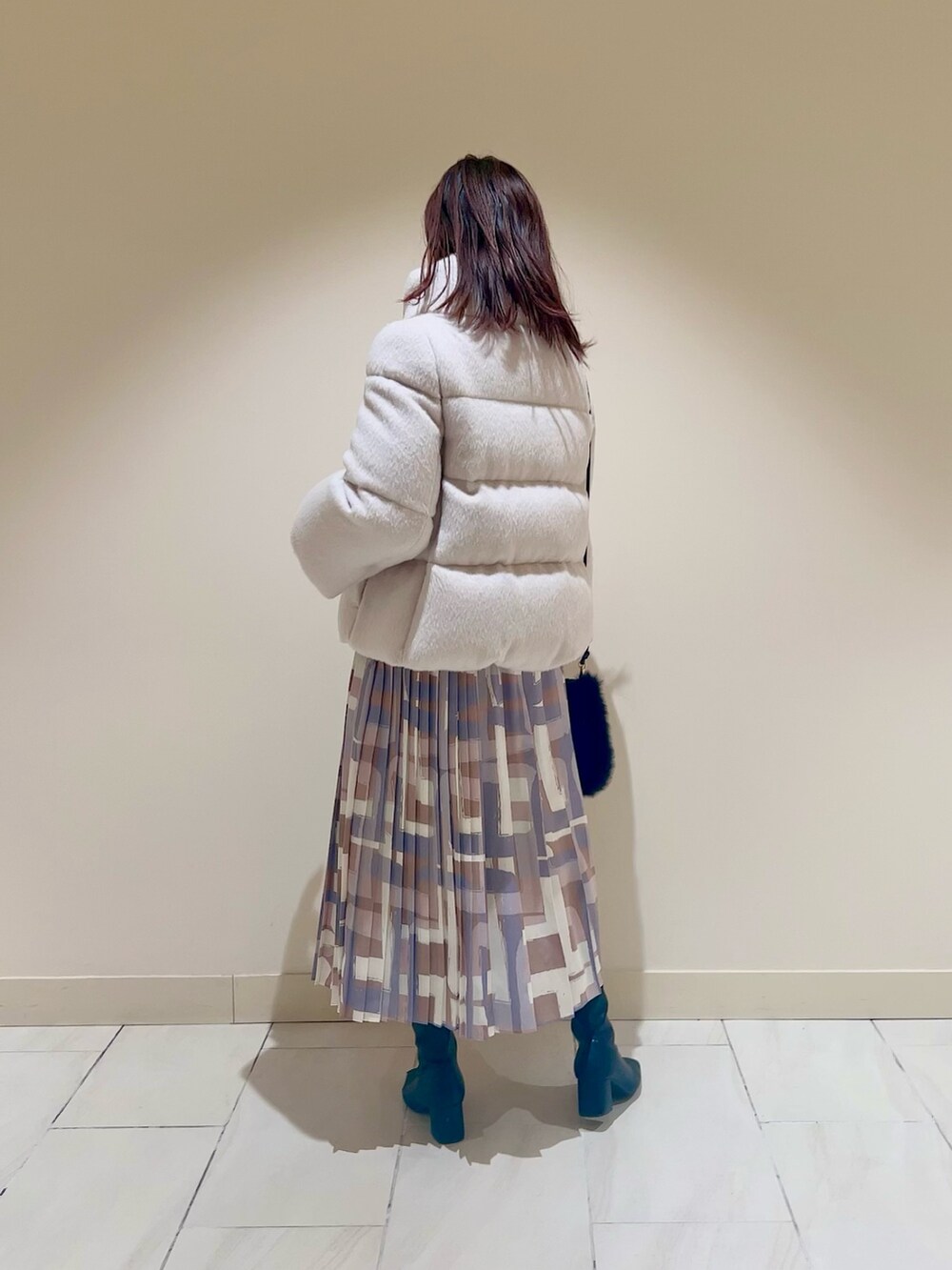 ホワイト系のダウンジャケット/コート、ブルー系のカーディガン/ボレロ、ベージュ系のスカートを着用したレディースの冬コーディネートの3枚目の写真