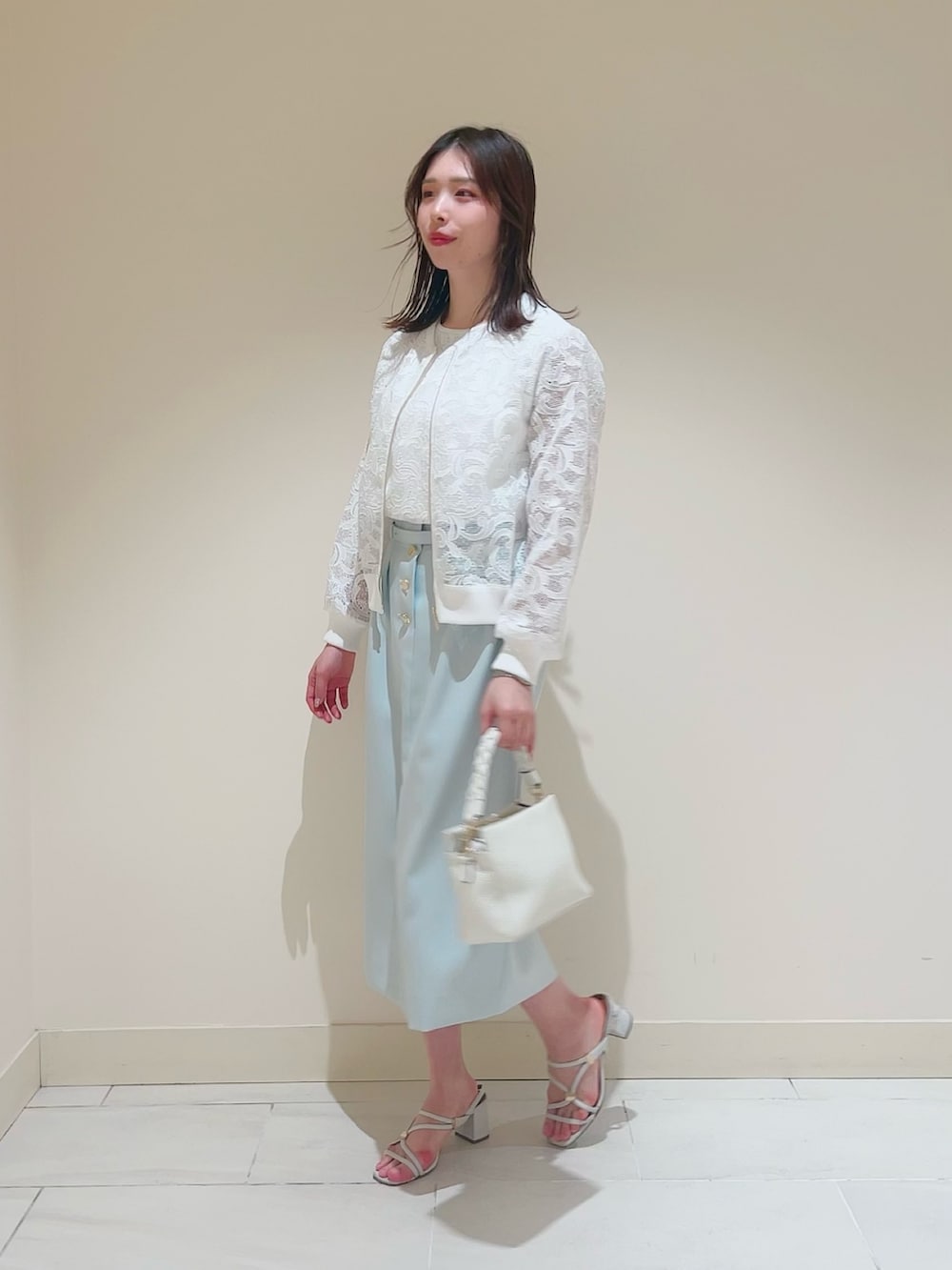 ホワイト系のニット/セーター、ホワイト系のその他トップス、グリーン系のスカートを着用したレディースの春コーディネートの2枚目の写真