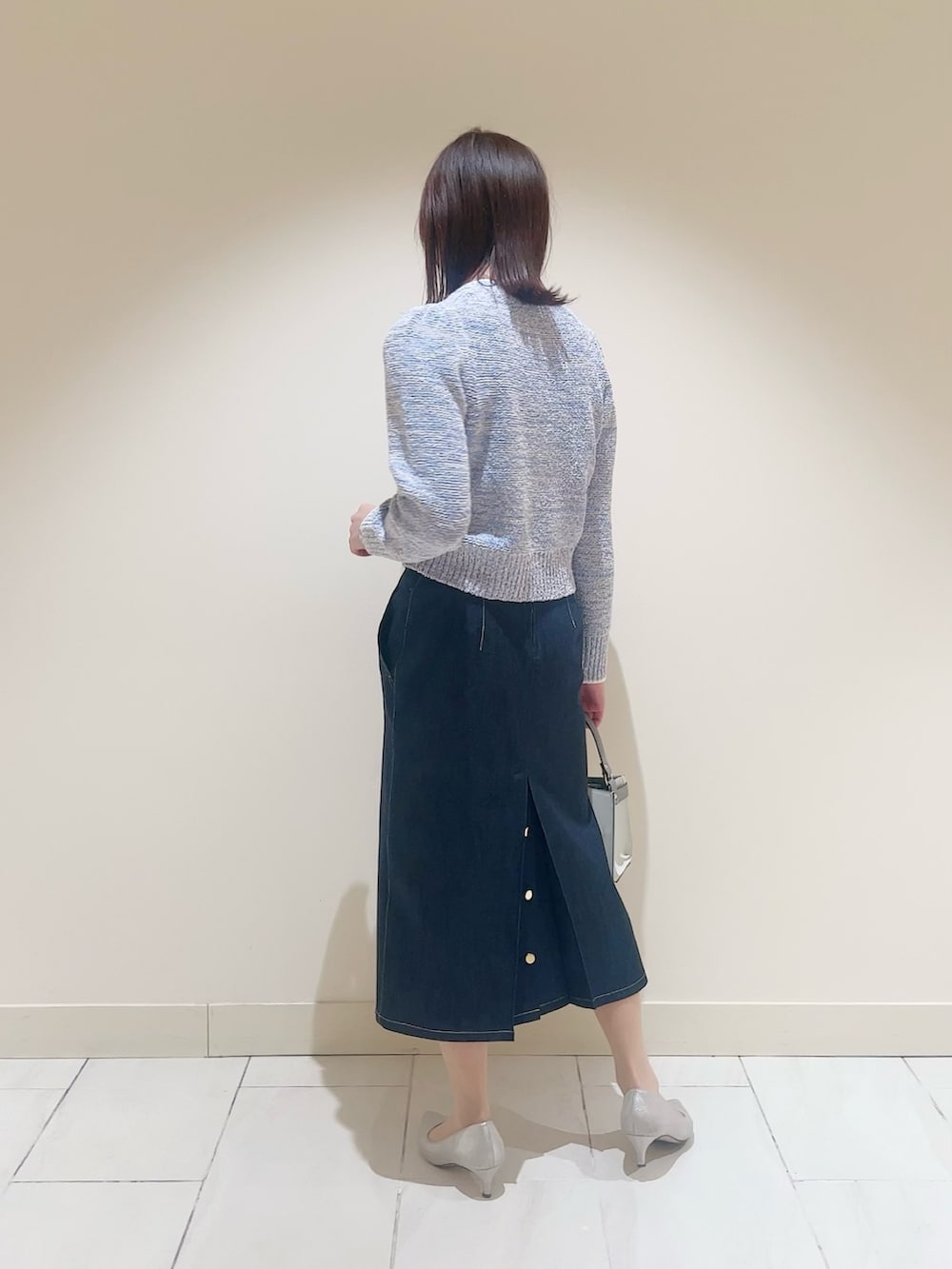 ホワイト系のハンドバッグ、ブルー系のニット/セーター、ブルー系のデニムスカートを着用したレディースの春コーディネートの3枚目の写真