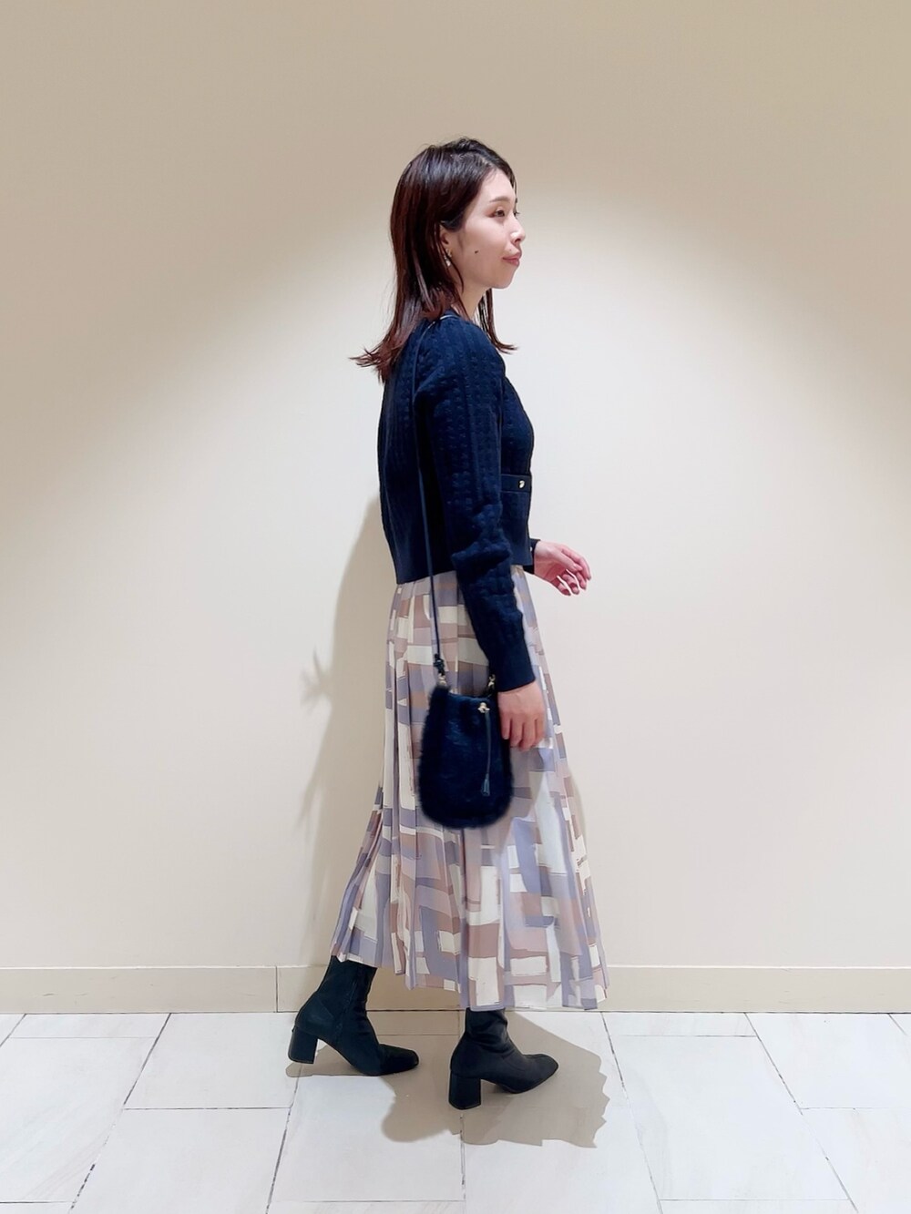 ホワイト系のダウンジャケット/コート、ブルー系のカーディガン/ボレロ、ベージュ系のスカートを着用したレディースの冬コーディネートの6枚目の写真