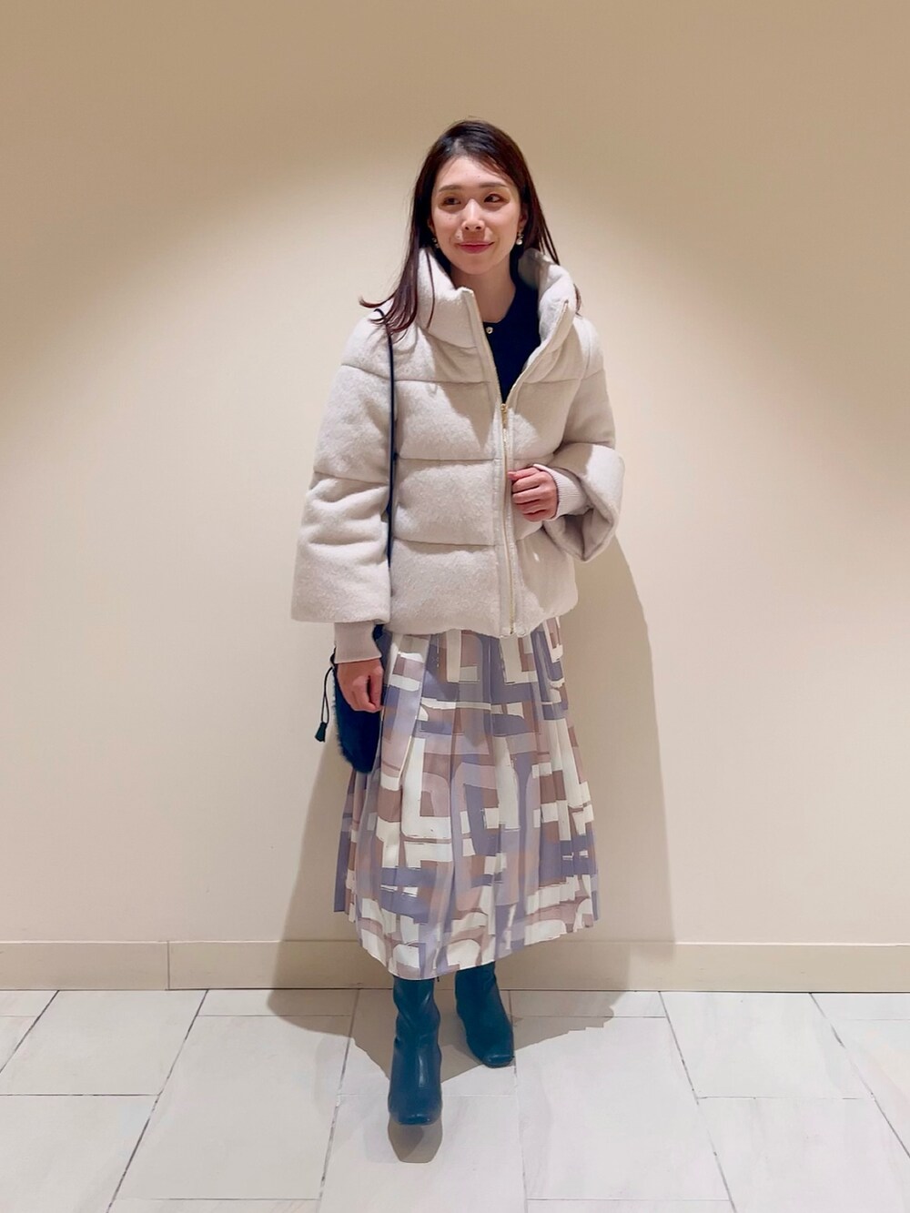 ホワイト系のダウンジャケット/コート、ブルー系のカーディガン/ボレロ、ベージュ系のスカートを着用したレディースの冬コーディネートの4枚目の写真