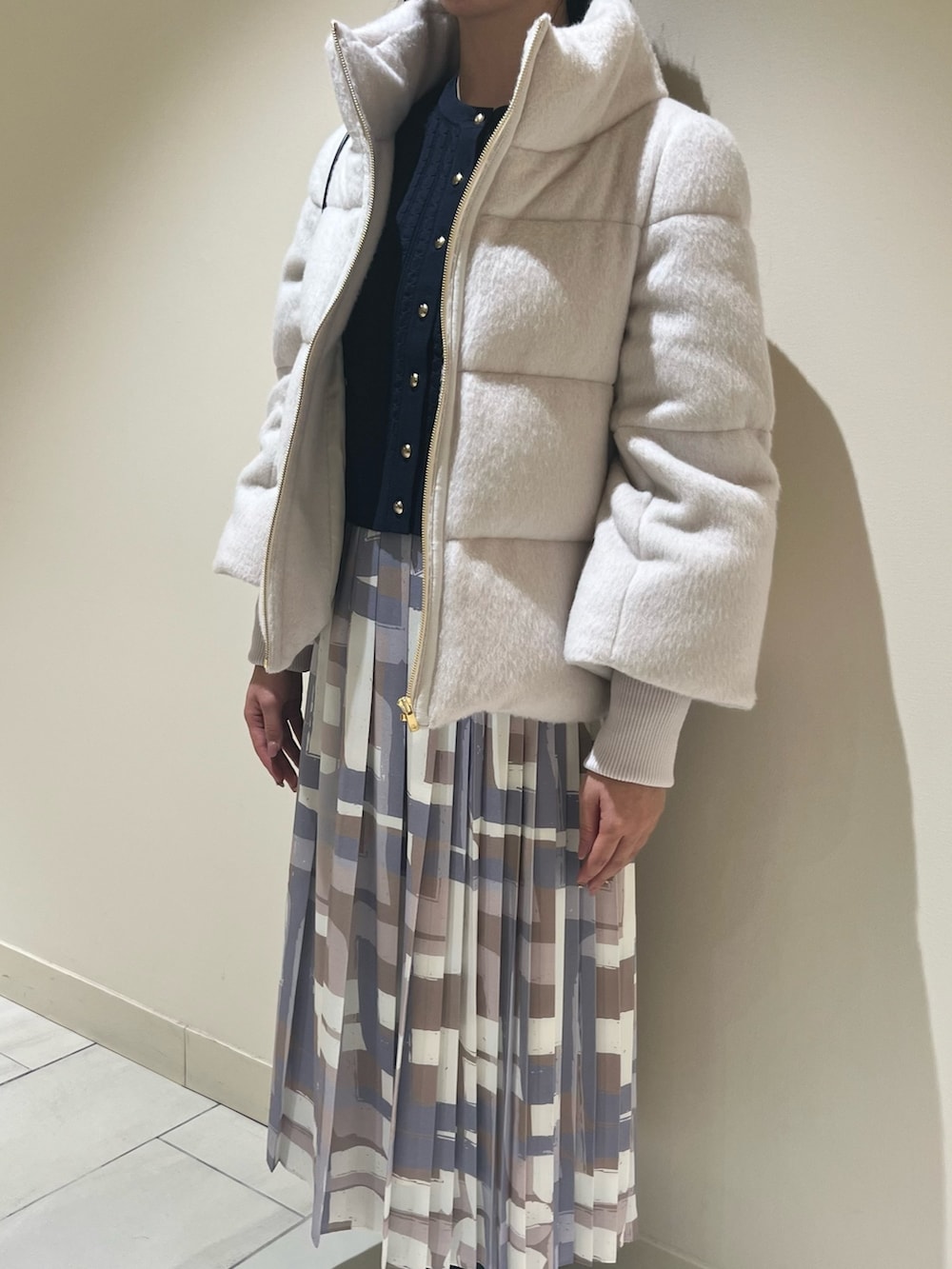 ホワイト系のダウンジャケット/コート、ブルー系のカーディガン/ボレロ、ベージュ系のスカートを着用したレディースの冬コーディネートの9枚目の写真