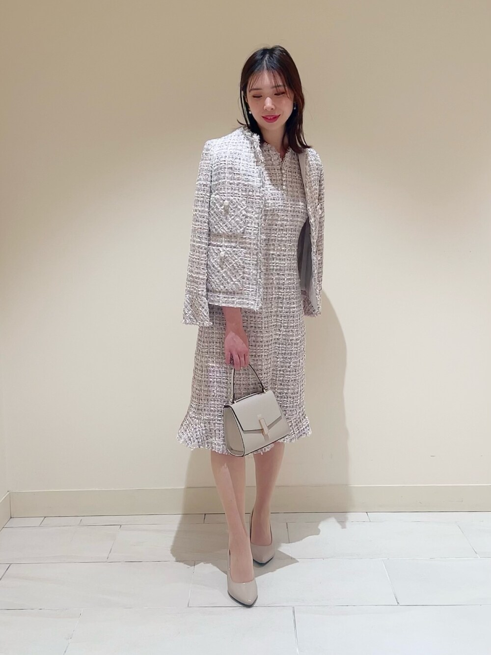 ベージュ系のトートバッグ、ピンク系のノーカラージャケット、ピンク系のワンピースを着用したレディースの春コーディネートの3枚目の写真
