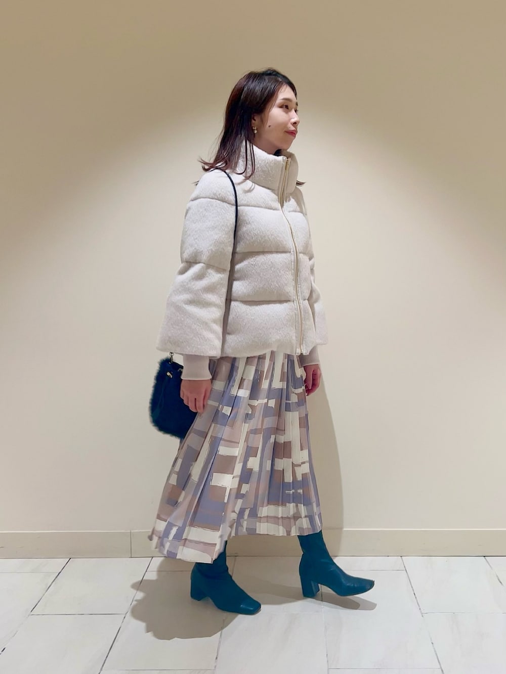 ホワイト系のダウンジャケット/コート、ブルー系のカーディガン/ボレロ、ベージュ系のスカートを着用したレディースの冬コーディネートの2枚目の写真