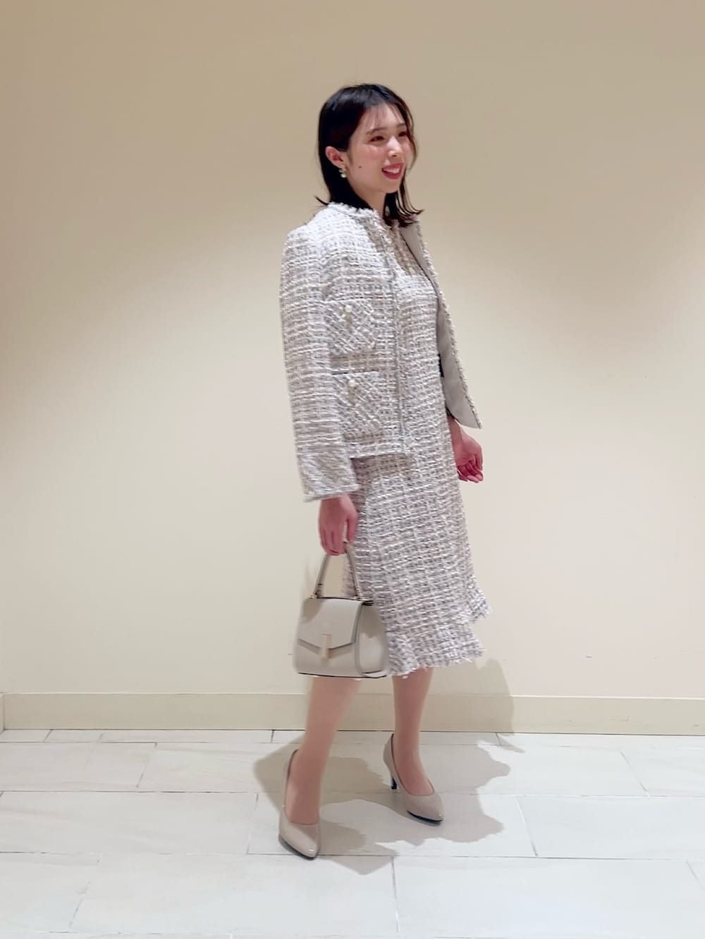 ベージュ系のトートバッグ、ピンク系のノーカラージャケット、ピンク系のワンピースを着用したレディースの春コーディネートの2枚目の写真