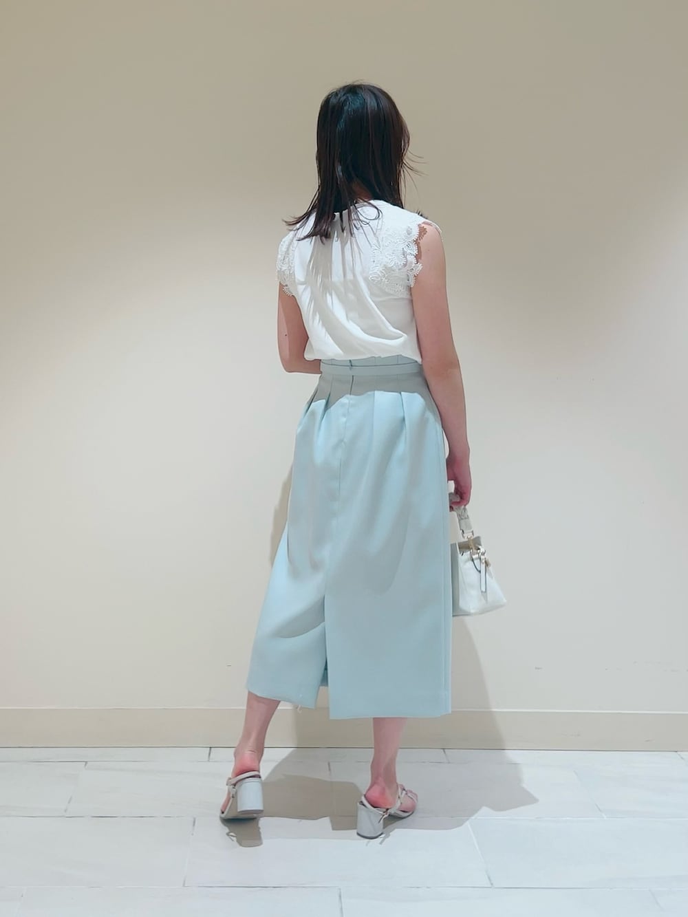 ホワイト系のニット/セーター、ホワイト系のその他トップス、グリーン系のスカートを着用したレディースの春コーディネートの6枚目の写真