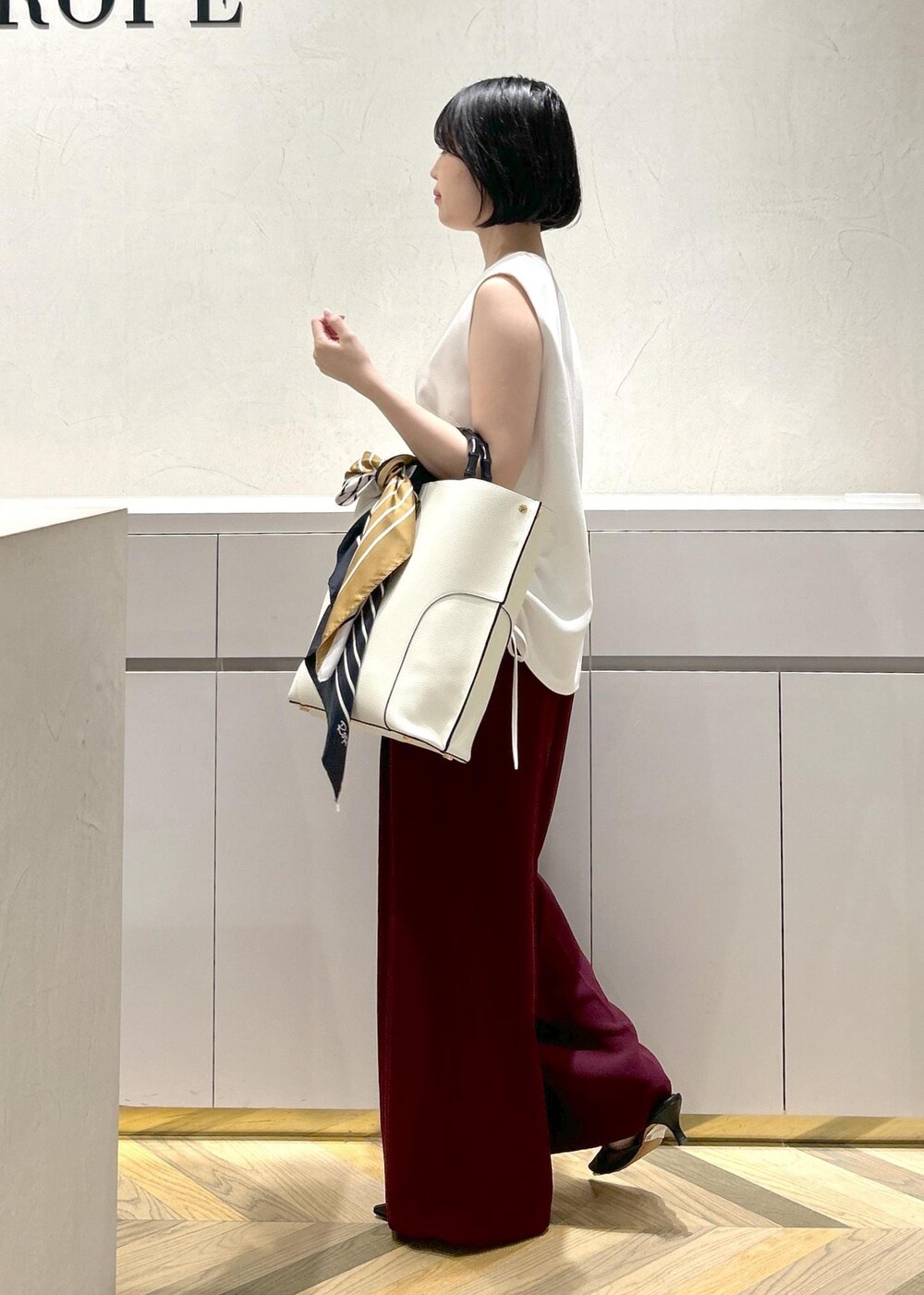 ホワイト系のトートバッグ、ブラック系のパンプス、レッド系のその他パンツを着用したレディースの夏コーディネートの2枚目の写真