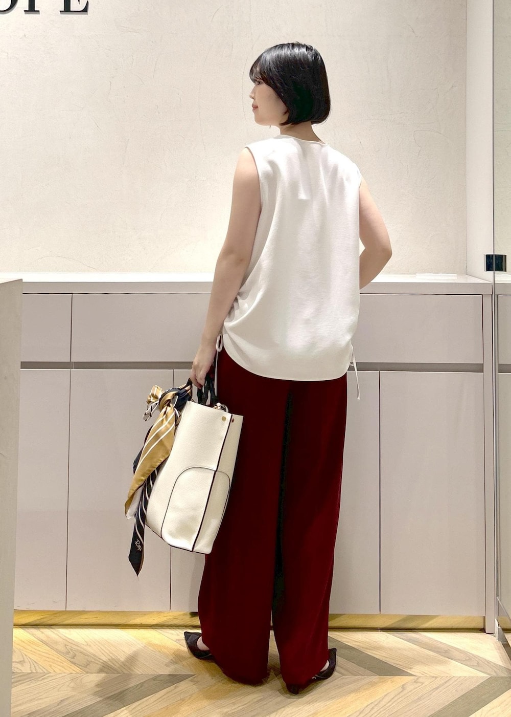 ホワイト系のトートバッグ、ブラック系のパンプス、レッド系のその他パンツを着用したレディースの夏コーディネートの3枚目の写真