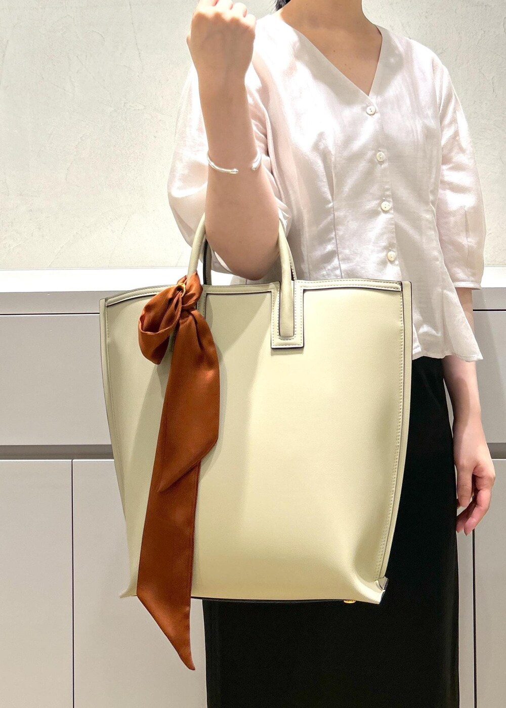 ブラック系のパンプス、ベージュ系のトートバッグ、ブラック系のスカートを着用したレディースの夏コーディネートの7枚目の写真