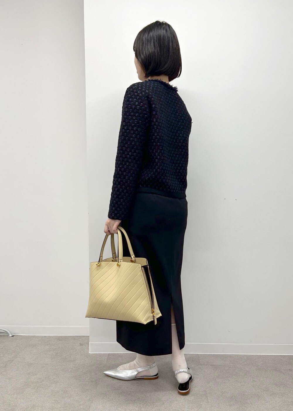 シルバー系のパンプス、ベージュ系のトートバッグ、ブラック系のスカートを着用したレディースの秋コーディネートの2枚目の写真
