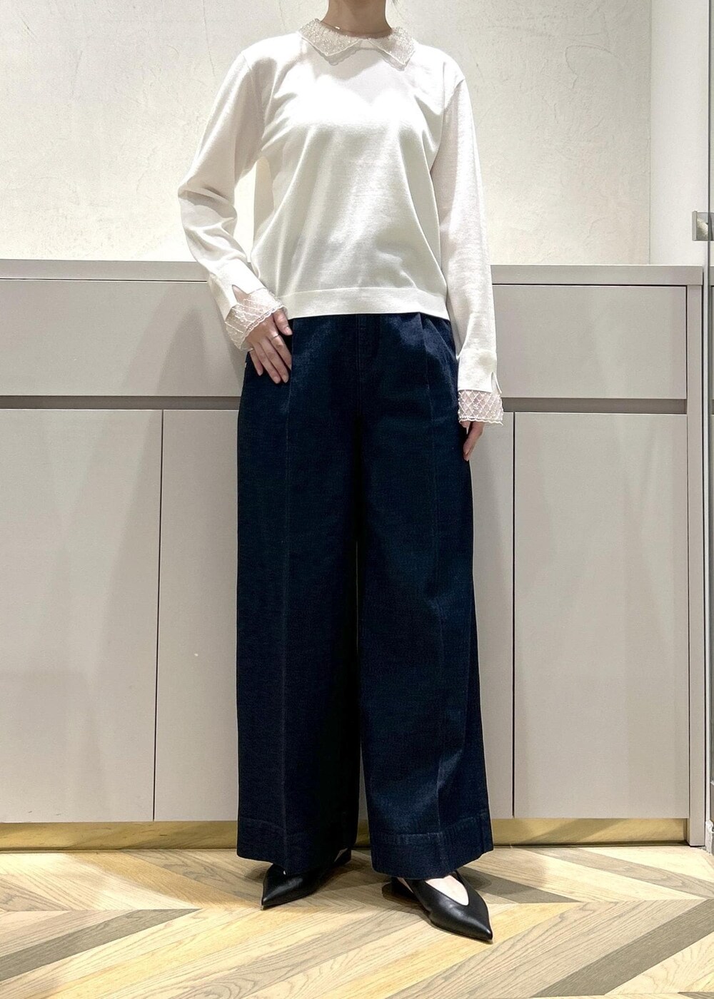 ブラック系のパンプス、ホワイト系のトートバッグ、ブルー系のデニムパンツを着用したレディースの冬コーディネートの4枚目の写真