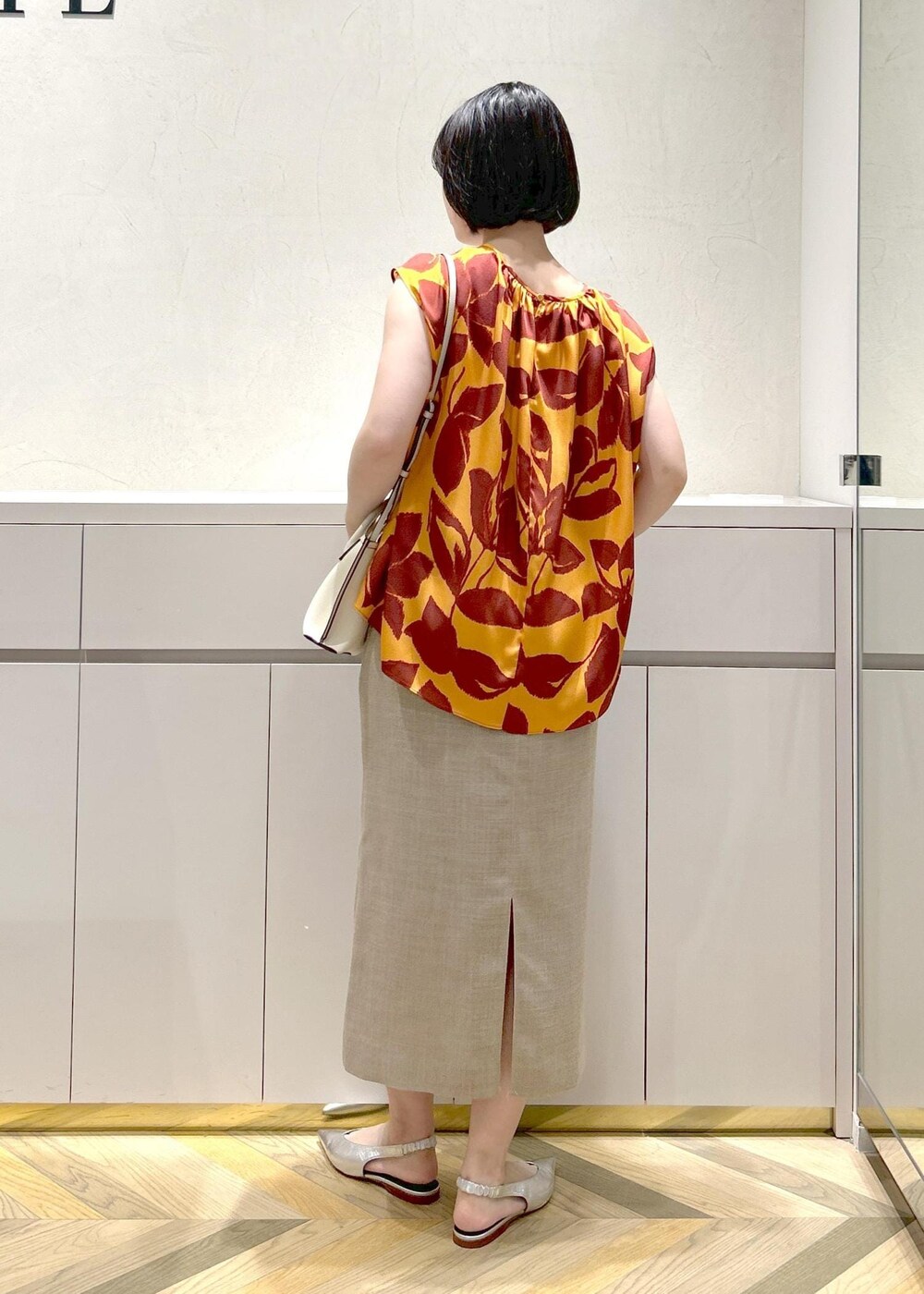 シルバー系のパンプス、ベージュ系のスカート、オレンジ系のシャツ/ブラウスを着用したレディースの夏コーディネートの3枚目の写真