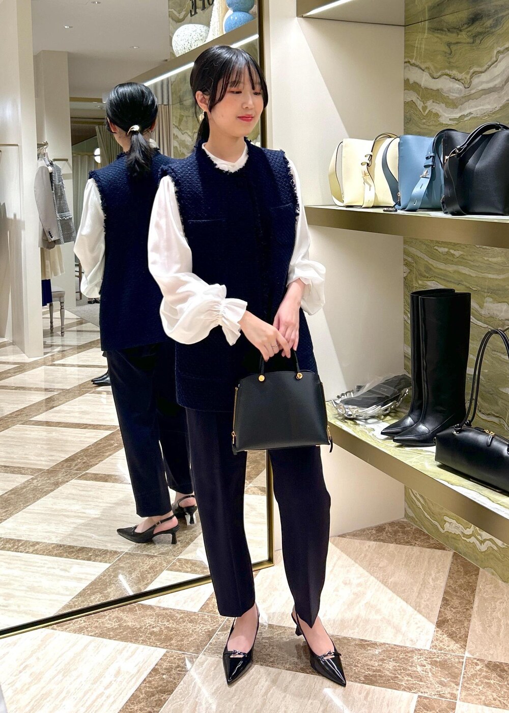 ブルー系のその他パンツ、ブラック系のパンプス、ブラック系のハンドバッグを着用したレディースの冬コーディネートの2枚目の写真