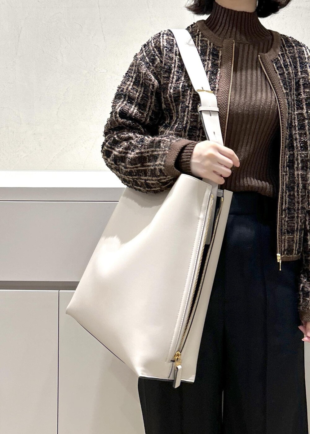 グレー系のショルダーバッグ、ブラウン系のニット/セーター、ブラック系のその他パンツを着用したレディースの秋コーディネートの7枚目の写真