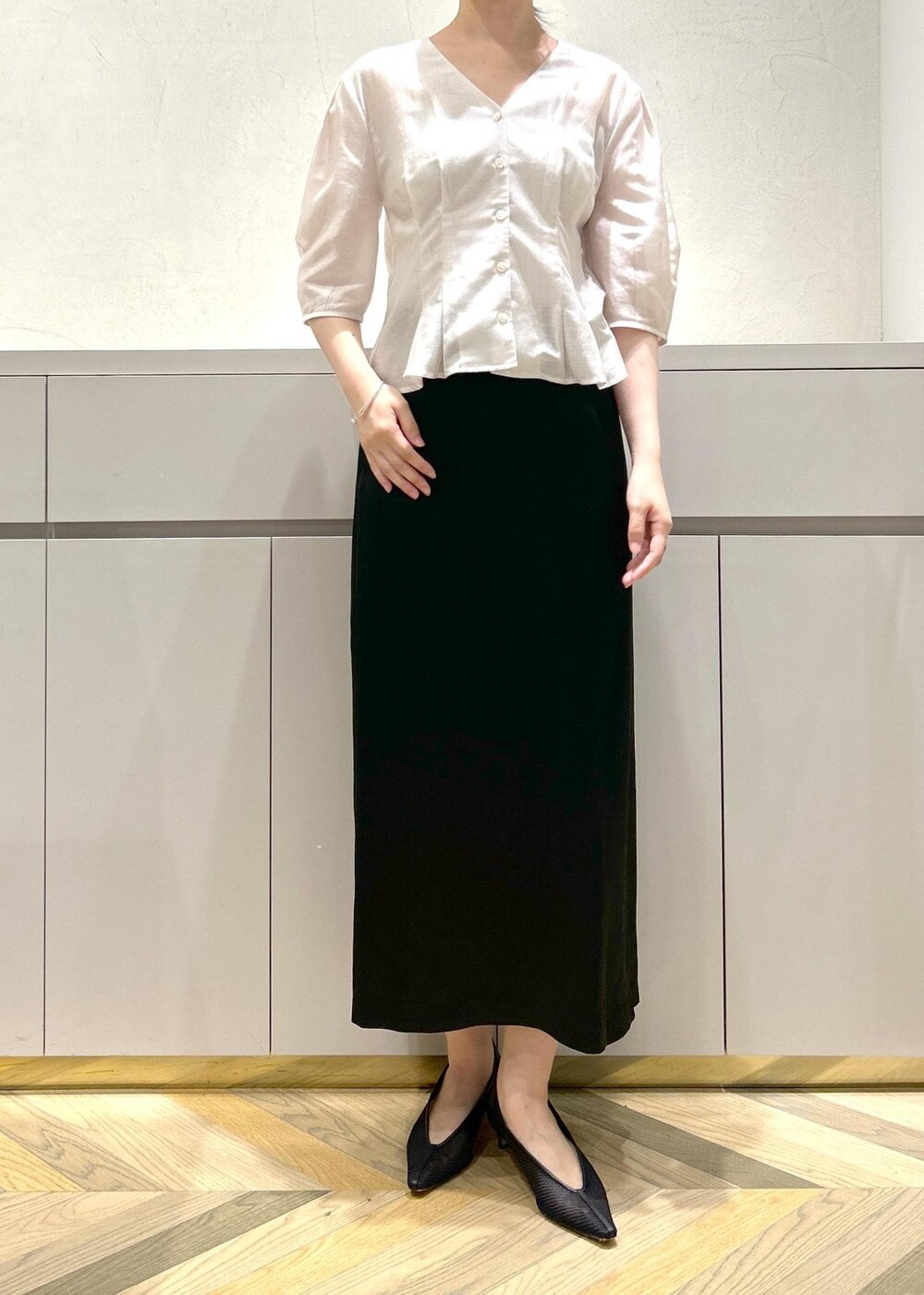 ブラック系のパンプス、ベージュ系のトートバッグ、ブラック系のスカートを着用したレディースの夏コーディネートの4枚目の写真