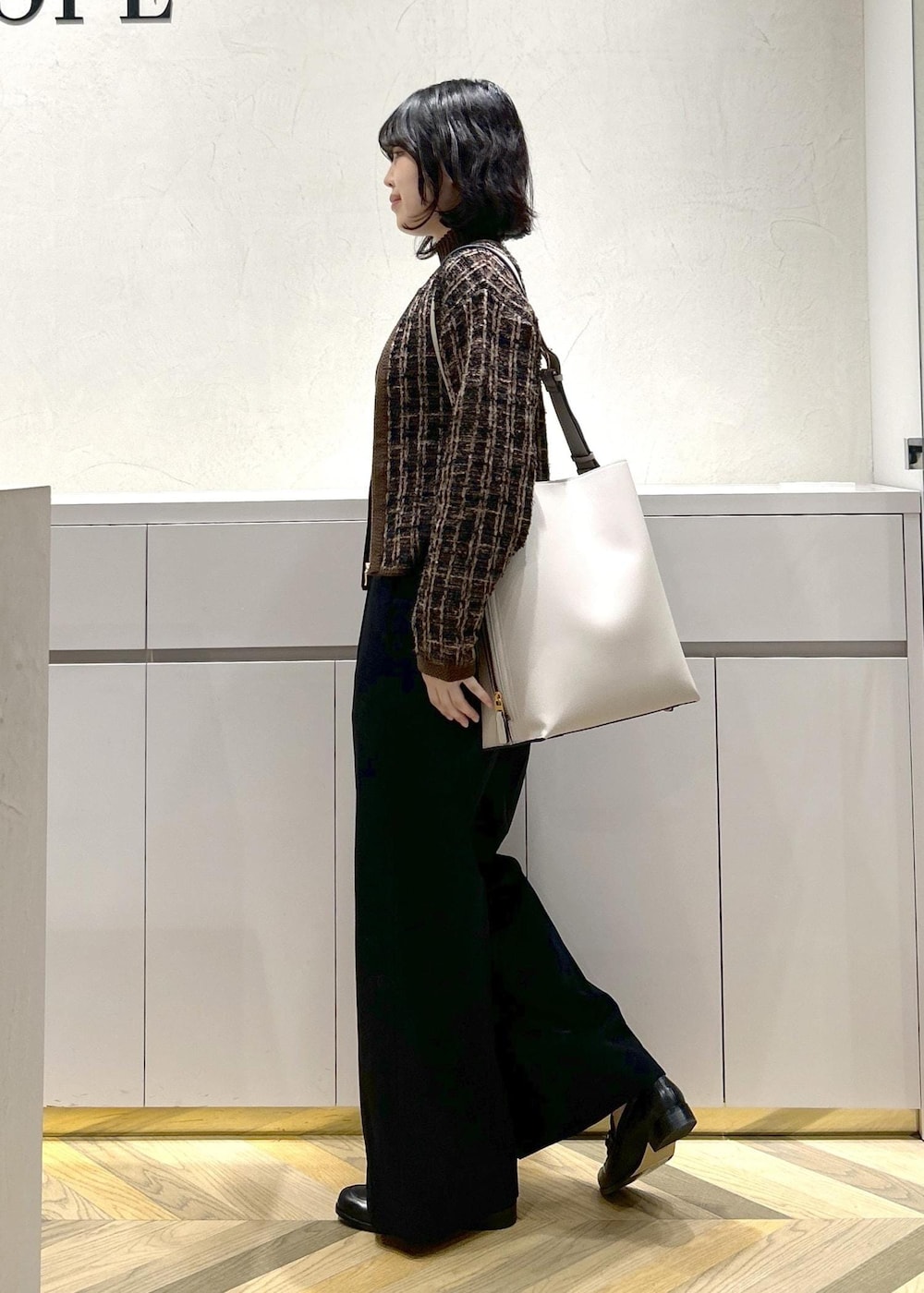 グレー系のショルダーバッグ、ブラウン系のニット/セーター、ブラック系のその他パンツを着用したレディースの秋コーディネートの2枚目の写真