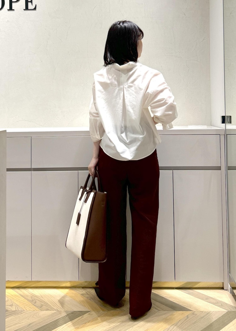 ブラウン系のトートバッグ、ホワイト系のシャツ/ブラウス、ブラック系のパンプスを着用したレディースの春コーディネートの3枚目の写真