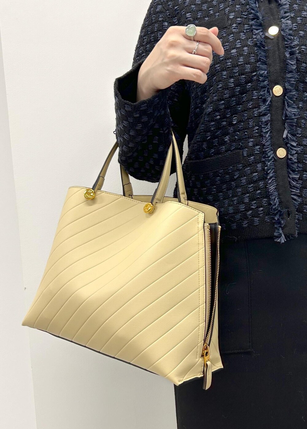 シルバー系のパンプス、ベージュ系のトートバッグ、ブラック系のスカートを着用したレディースの秋コーディネートの5枚目の写真