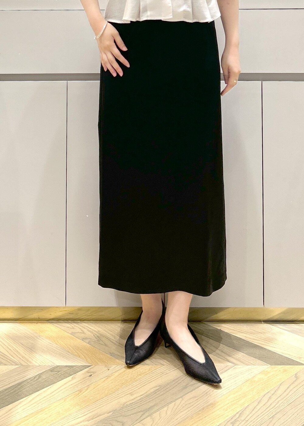 ブラック系のパンプス、ベージュ系のトートバッグ、ブラック系のスカートを着用したレディースの夏コーディネートの6枚目の写真