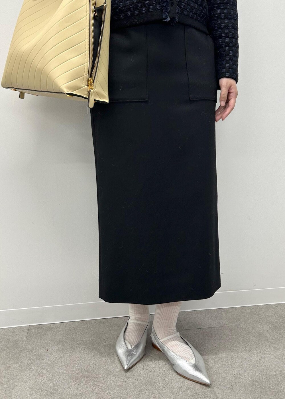 シルバー系のパンプス、ベージュ系のトートバッグ、ブラック系のスカートを着用したレディースの秋コーディネートの6枚目の写真