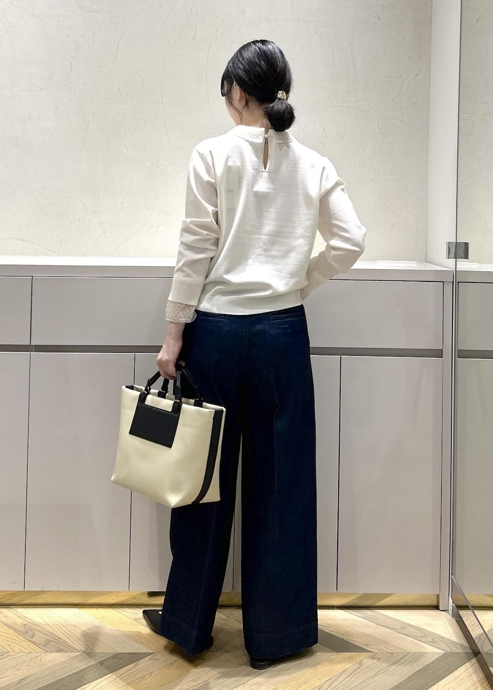 ブラック系のパンプス、ホワイト系のトートバッグ、ブルー系のデニムパンツを着用したレディースの冬コーディネートの3枚目の写真