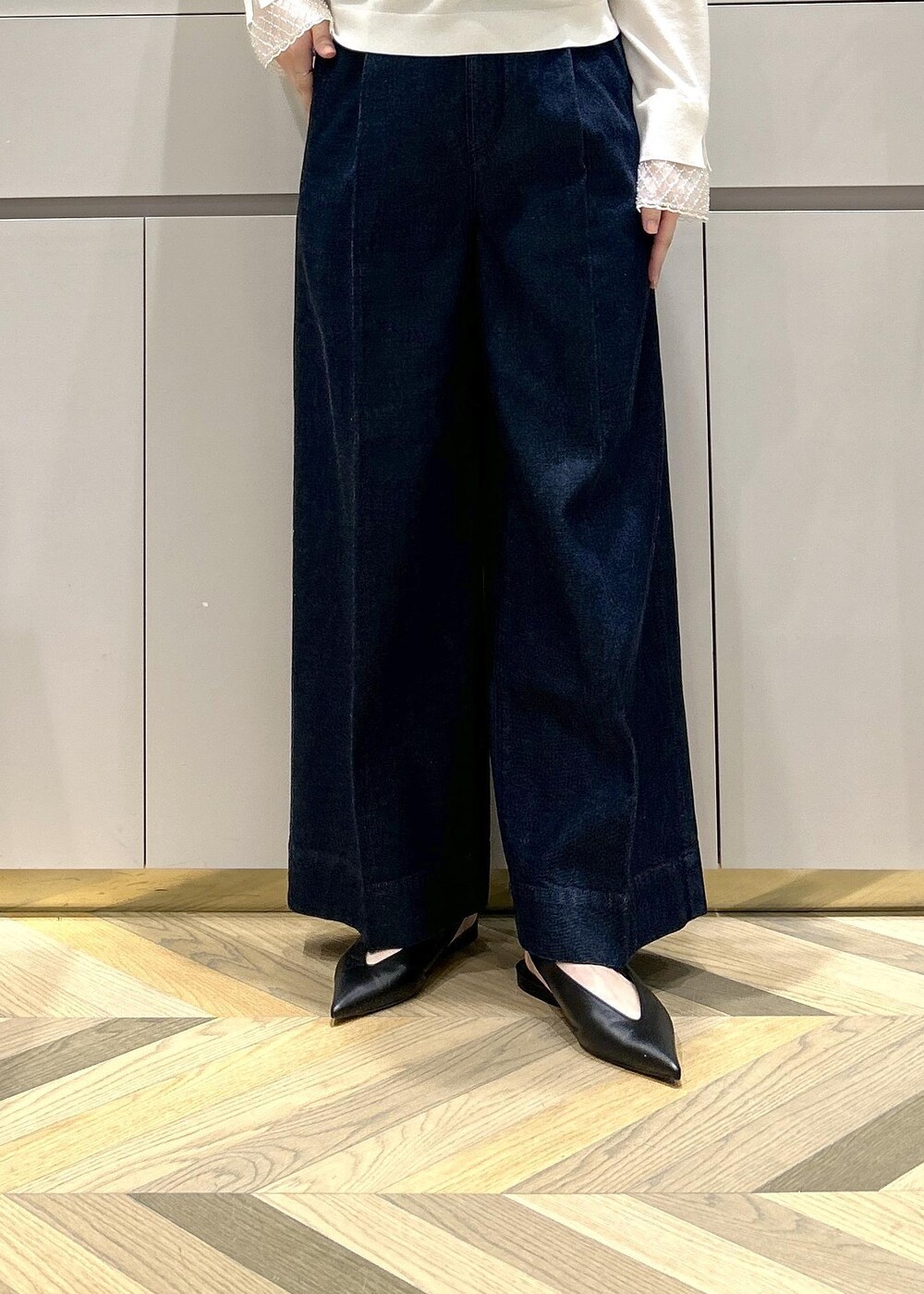 ブラック系のパンプス、ホワイト系のトートバッグ、ブルー系のデニムパンツを着用したレディースの冬コーディネートの6枚目の写真