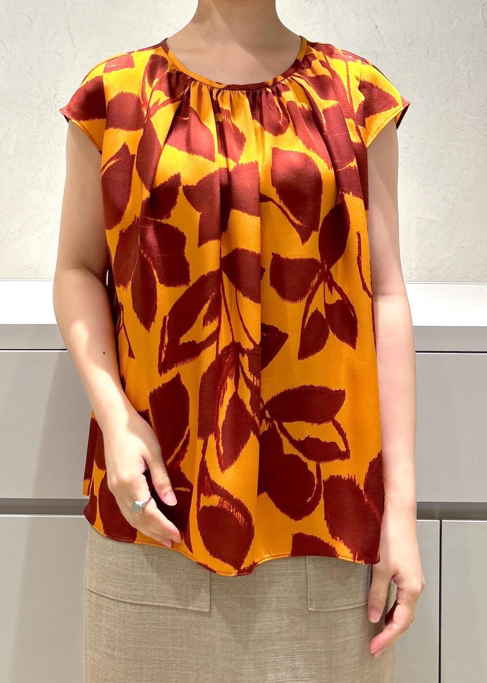 シルバー系のパンプス、ベージュ系のスカート、オレンジ系のシャツ/ブラウスを着用したレディースの夏コーディネートの6枚目の写真