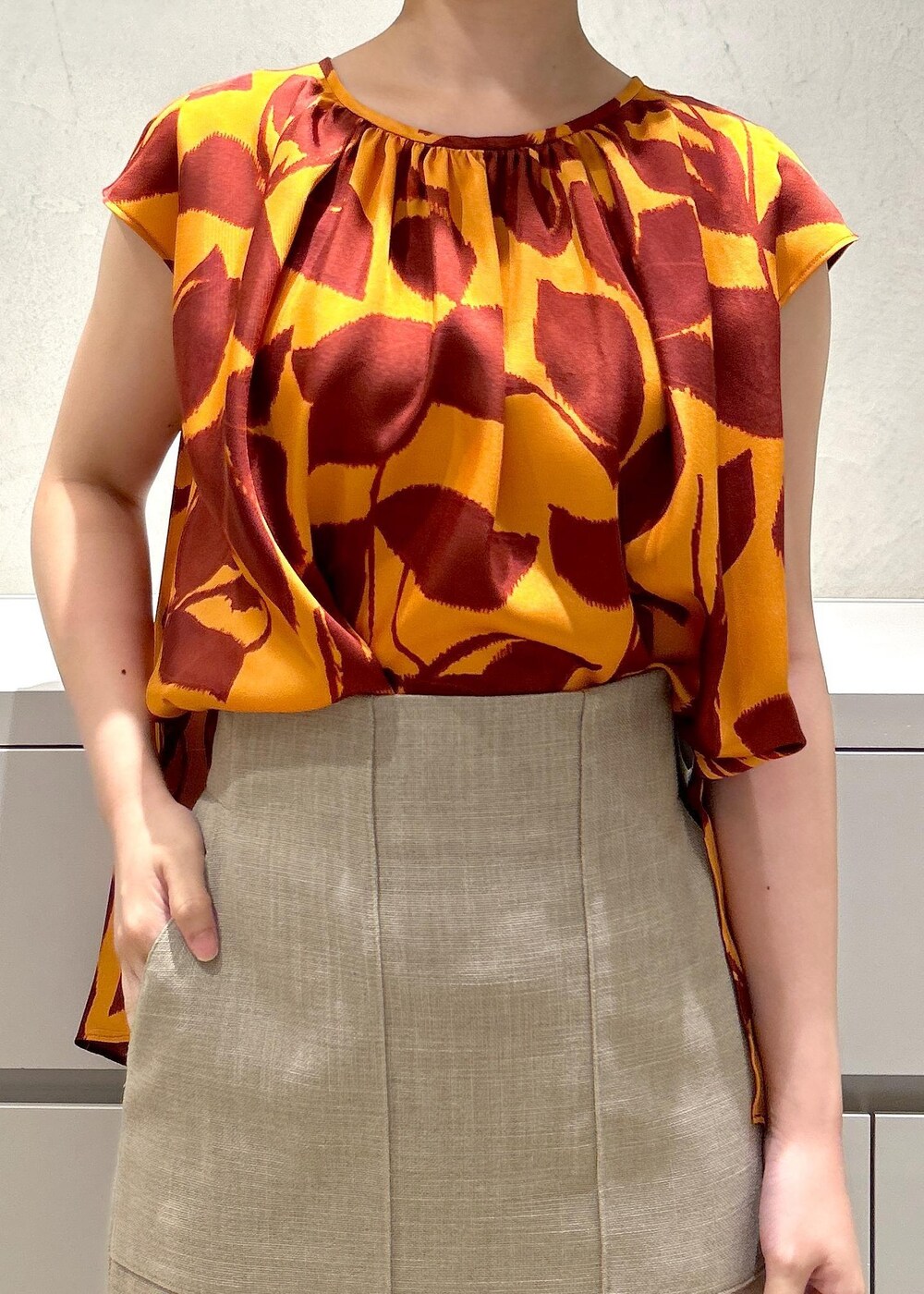 シルバー系のパンプス、ベージュ系のスカート、オレンジ系のシャツ/ブラウスを着用したレディースの夏コーディネートの5枚目の写真