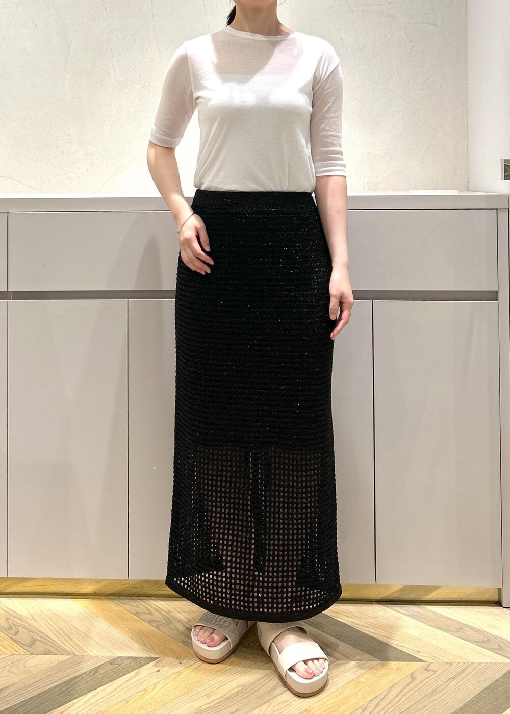 ホワイト系のハンドバッグ、ベージュ系のサンダル、ホワイト系のTシャツ/カットソーを着用したレディースの夏コーディネートの4枚目の写真